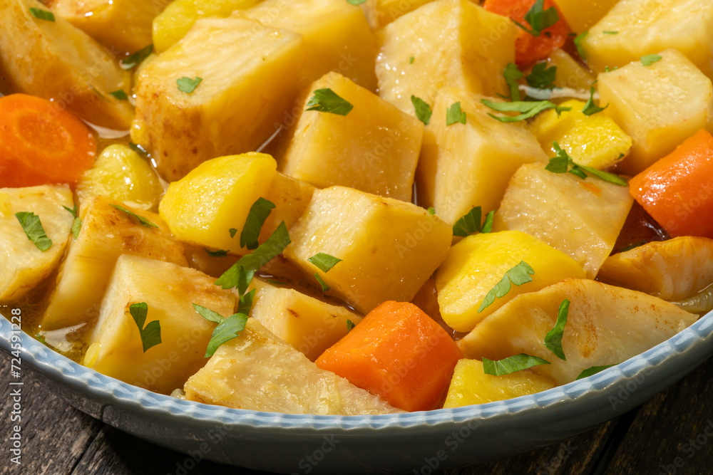 Close-up view of Turkish-style braised celeriac (Zeytinyağlı kereviz) in bowl on rustic wooden table. Close-up view of Turkish-style braised celeriac (Zeytinyağlı kereviz) in bowl on rustic wooden table.