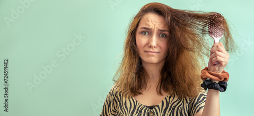 A woman struggling with fizzy hair combing, holding a hair brush. Banner with space for text.