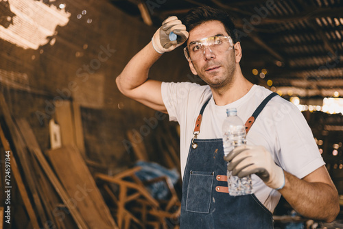 Tired stress carpenter man worker sweating hot workplace hardwork drinking water brake relax dehydrate in wood furniture workshop.