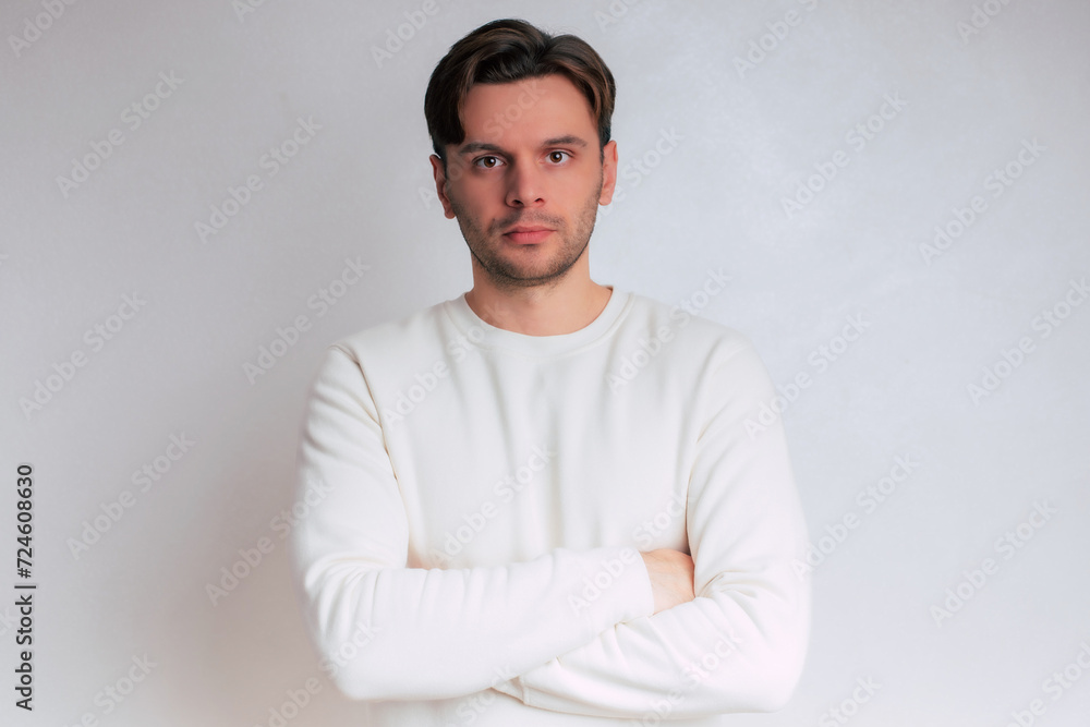 Close up portrait of young handsome confident man in casual clothes with crossed and folded arms isolated on gray background Close up portrait of young handsome confident man in casual clothes with crossed and folded arms isolated on gray background