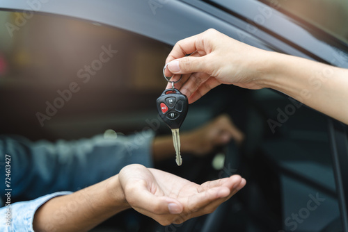 Buy second-hand auto or rent a car concept, Close-up hand of used car agent giving an auto key to client. photo