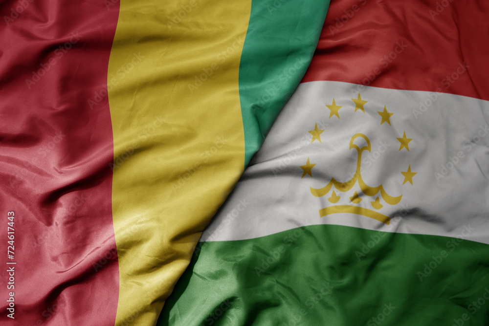 big waving national colorful flag of tajikistan and national flag of guinea . big waving national colorful flag of tajikistan and national flag of guinea .