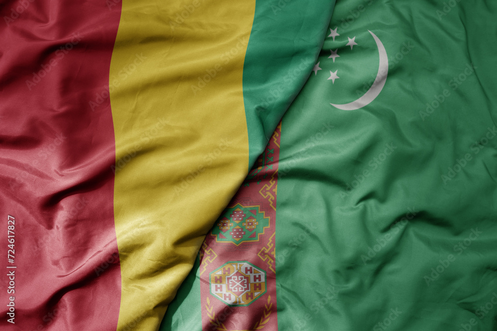 big waving national colorful flag of turkmenistan and national flag of guinea .