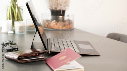 Man typing on laptop with German passport and wallet in frame photo