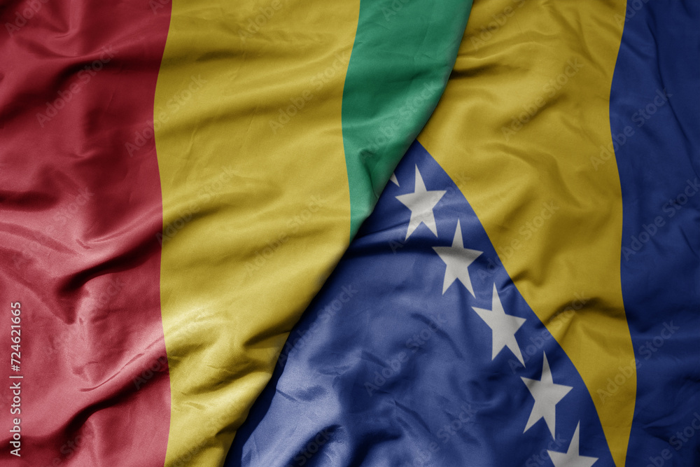 big waving national colorful flag of bosnia and herzegovina and national flag of guinea . big waving national colorful flag of bosnia and herzegovina and national flag of guinea .