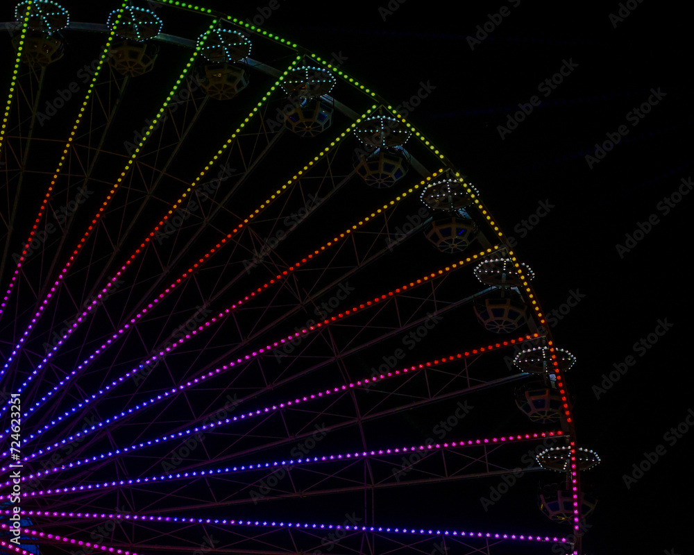 ferris wheel with colored lights in an amusement park at night on a black background