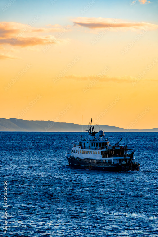 Vessel cruising towards horizon on adriatic sea (Mediterranean Sea) near Split and Brac island. Idyllic and colorful sunset atmosphere in popular holiday destination in Croatia. Yachting vacations.