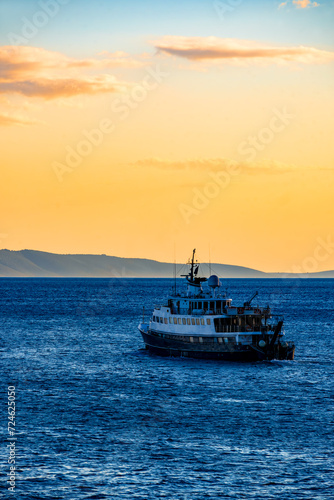 Vessel cruising towards horizon on adriatic sea (Mediterranean Sea) near Split and Brac island. Idyllic and colorful sunset atmosphere in popular holiday destination in Croatia. Yachting vacations.