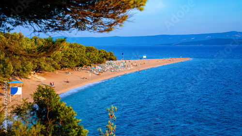 “Zlatni rat“ panorama – popular and famous beach in Bol on Brac island in Croatia. Sandy spit of land or tongue reaching into adriatic sea (Mediterranean Sea) at sunset with warm light in summer. photo