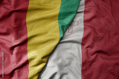 big waving national colorful flag of malta and national flag of guinea .