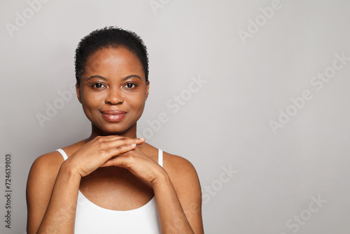 Lovely African American female model with healthy fresh clear dark skin posing on white background. Skin care, cosmetology and beauty treatment