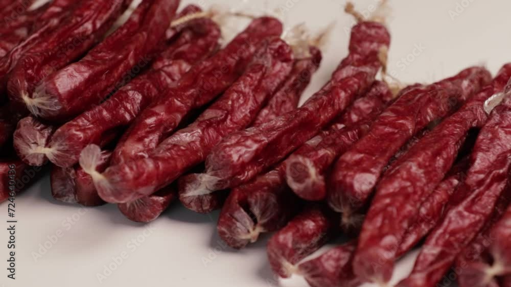 Thin smoked sausages (cabanos) on a white background. Horizontal camera movement.. Thin smoked sausages (cabanos) on a white background. Horizontal camera movement..