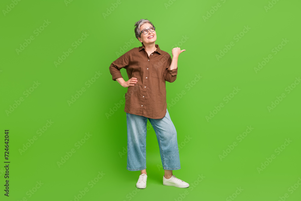 Full size photo of retired person dressed stylish shirt in eyewear look directing at promo empty space isolated on green color background Full size photo of retired person dressed stylish shirt in eyewear look directing at promo empty space isolated on green color background