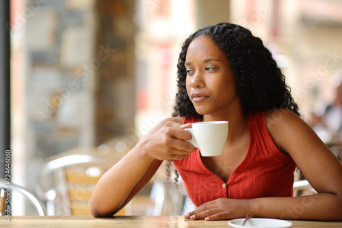 Serious black woman drinking coffee looking away