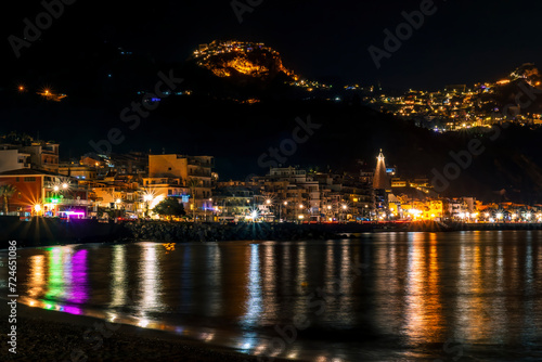 night town coast with flashlights from embarkment and reflection in sea gulf water with golden urbal lights on background of landscape photo