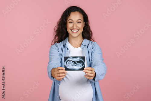 Happy young pregnant woman showing sonogram of her baby photo