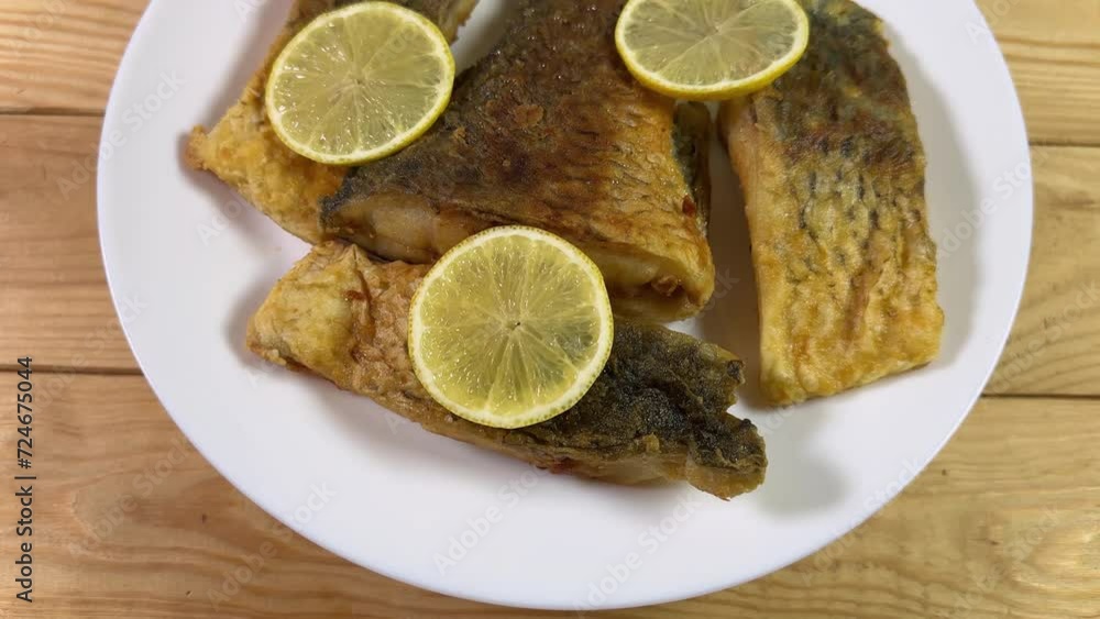 Fried carp pieces with lemon on dish on rustic table Fried carp pieces with lemon on dish on rustic table