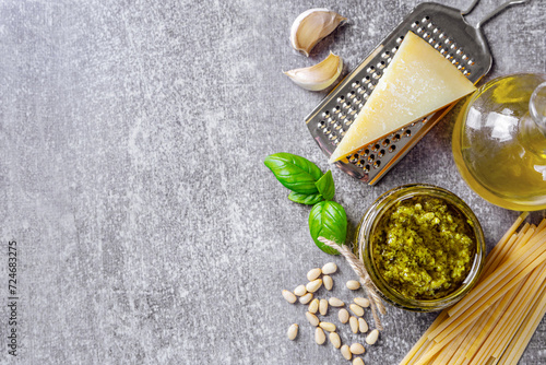 Fototapeta Naklejka Na Ścianę i Meble -  Homemade pesto sauce in small jar and ingredients for pasta on gray concrete background with copy space. Traditional Italian cuisine, recipe, restaurant menu, banner, header
