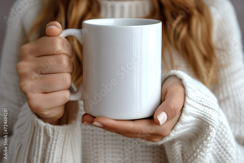 Person in a sweater holding a white mug in focus