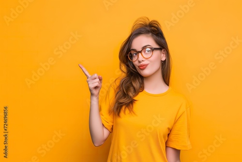 A young girl on an orange studio background gestures with her finger raised. photo
