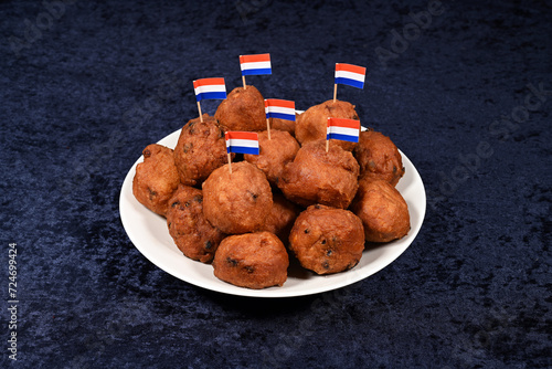 Bowl of oliebollen with flags of The Netherlands on a red kitchen towel. Oliebol is a Dutch traditional beignet for new years eve.
