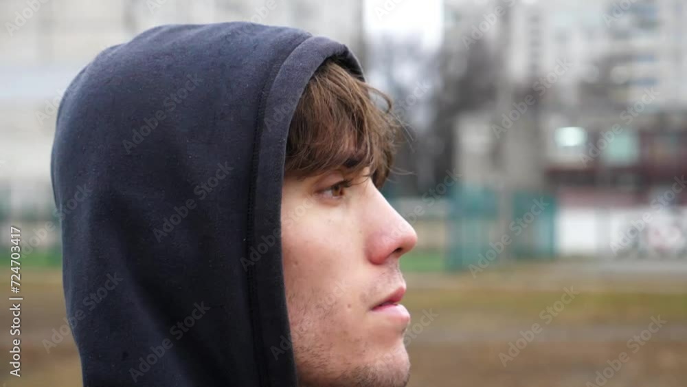 Athletic man in sportswear fixing hood on his head and preparing to training in rain. Young male runner working out at cloudy day. Strong sportsman exercising outdoor. Concept of sportive lifestyle Athletic man in sportswear fixing hood on his head and preparing to training in rain. Young male runner working out at cloudy day. Strong sportsman exercising outdoor. Concept of sportive lifestyle