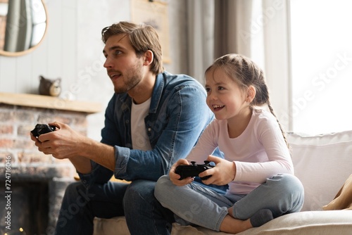 Young man and little girl playing computer game with gaming console. photo