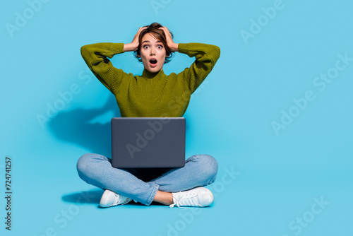 Photo of impressed girl wear trendy clothes sit floor arms touch head omg unexpected news empty space isolated on cyan color background © deagreez