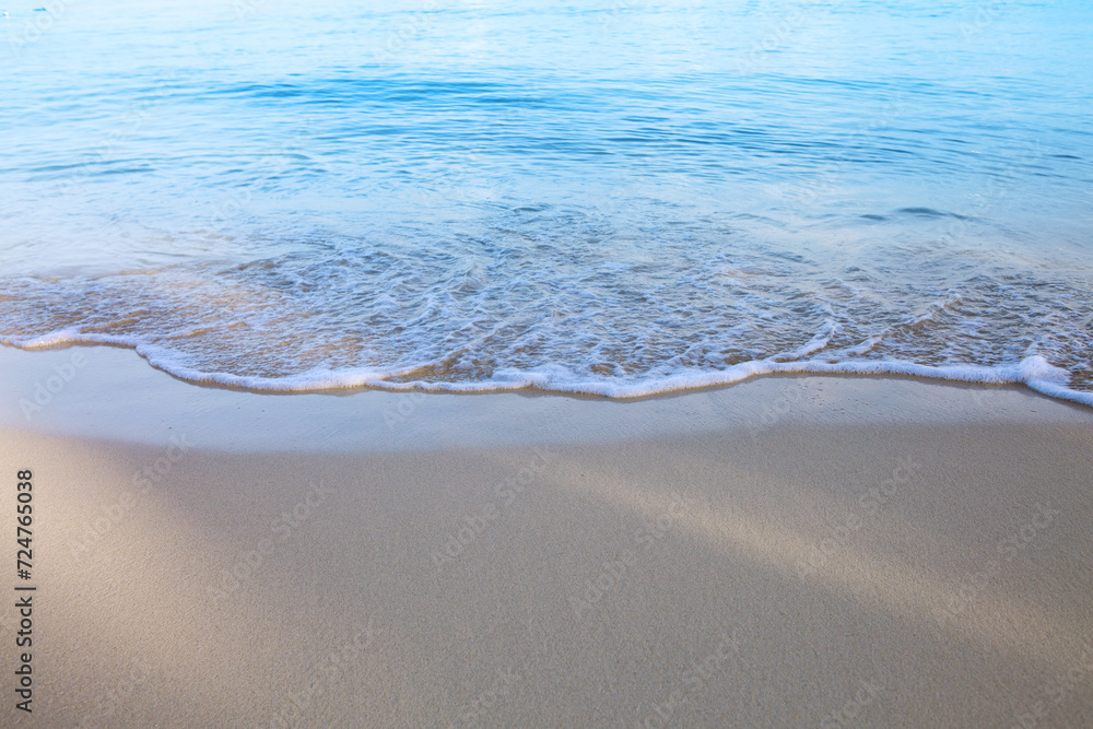 Travel background with soft wave of blue ocean on sandy beach.