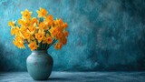  a vase filled with yellow daffodils on a table next to a teal blue wall and a blue wall behind the vase is a blue vase with yellow daffodils.