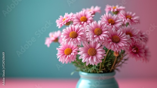  a blue vase filled with pink daisies on top of a pink and blue tableclothed tablecloth and a blue wall behind the vase is filled with pink daisies.