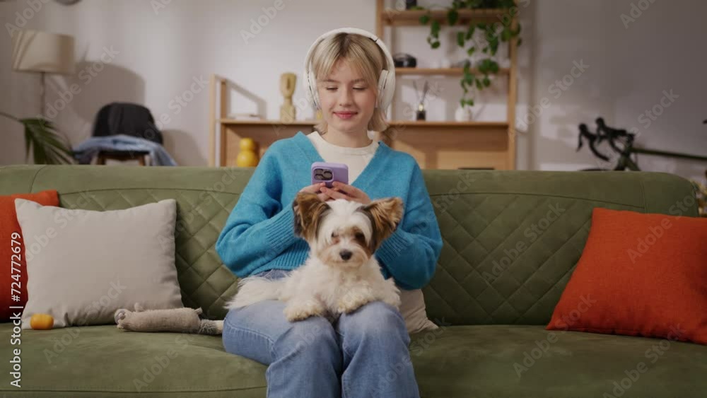 Caring female looking at phone screen with dog next to her Caring female looking at phone screen with dog next to her