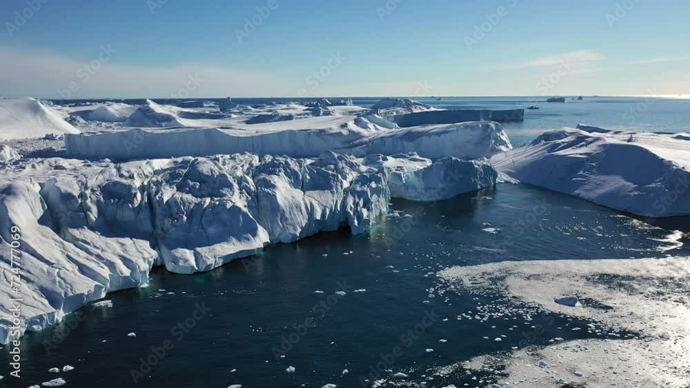 Ice desert shot from above. Polar iceland winter landscape aerial panorama. Frozen ocean, glaciers, icebergs, blue sky in sunny day. Wilderness of Antarctica, South Pole. Desert white land of ice.