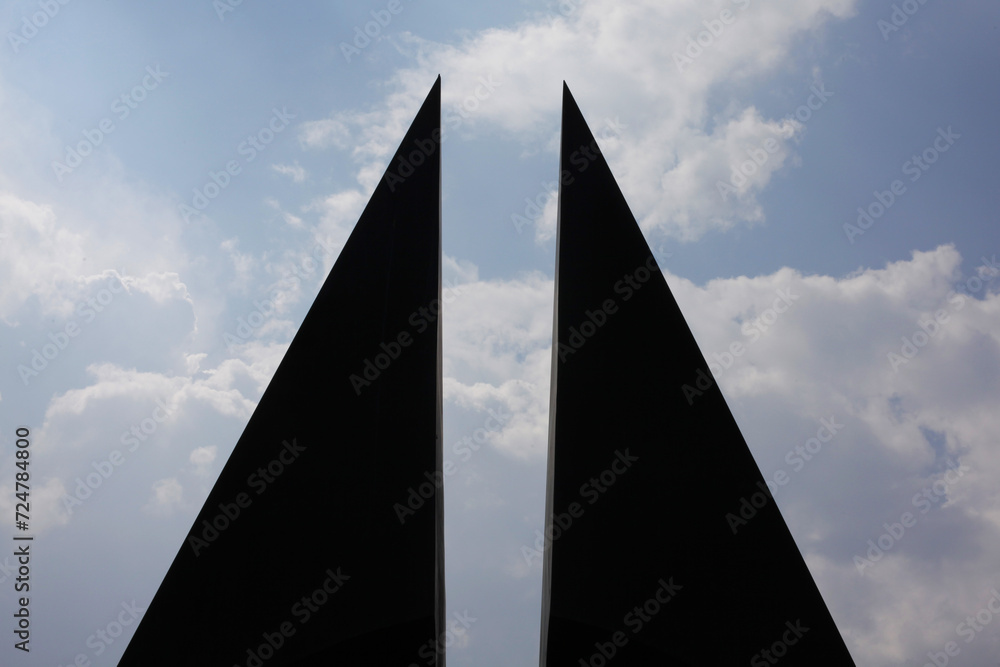 Two black triangles facing each other on the clouds background