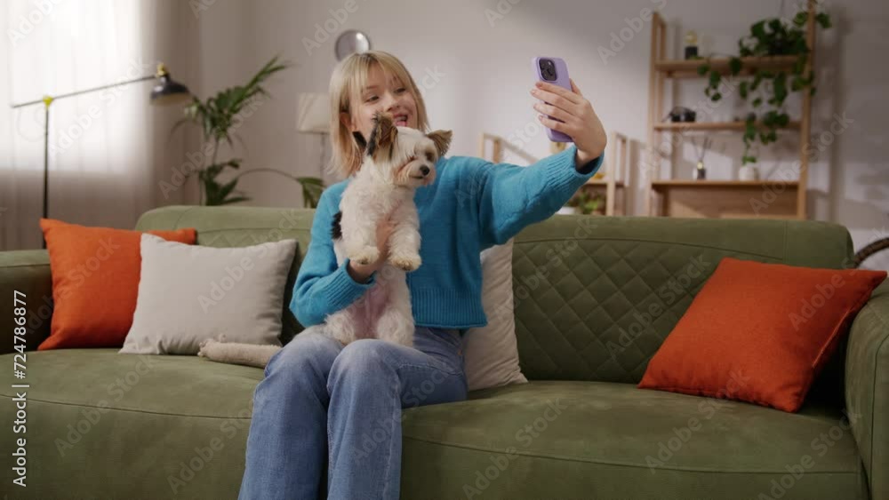 Female taking pictures with cell phone while holding puppy Female taking pictures with cell phone while holding puppy