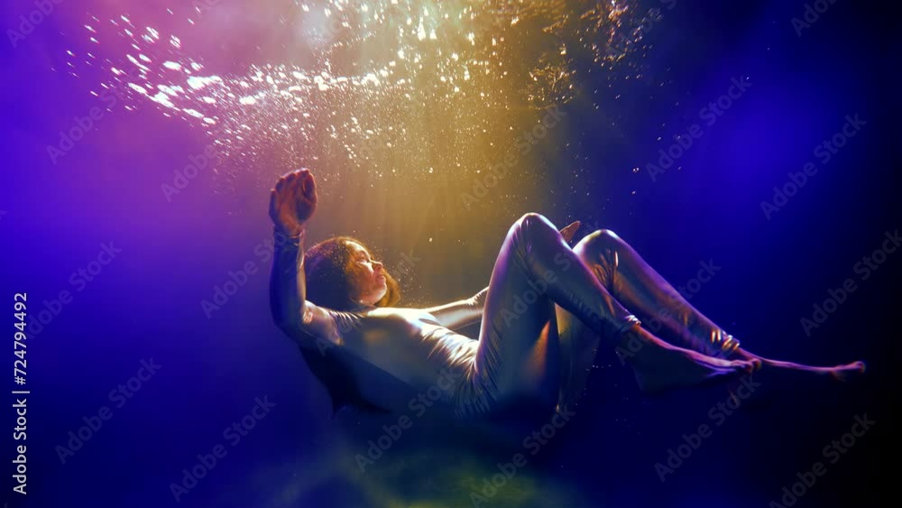In a dream underwater, an adult woman is like a space fairy, whose magic blossoms in her every move, her silver jumpsuit becomes a bridge between worlds. In a dream underwater, an adult woman is like a space fairy, whose magic blossoms in her every move, her silver jumpsuit becomes a bridge between worlds.