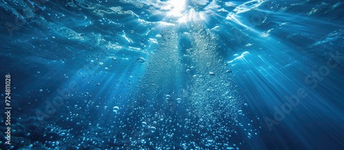 Underwater bubbles allow sunlight to penetrate the azure ocean depths dark blue. 