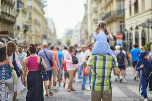 Father holding daughter on shoulders and walking on a street of Paris, France photo