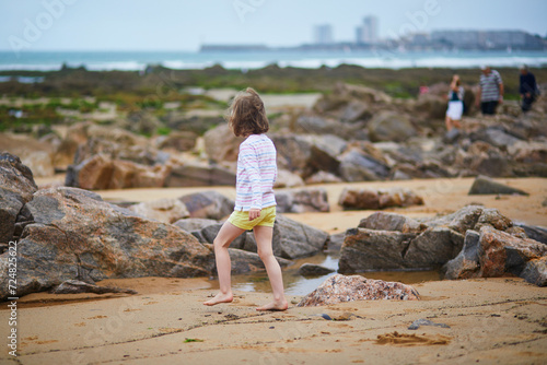 Adorable preschooler girl playing on the beach at Atlantic coast of Brittany, France