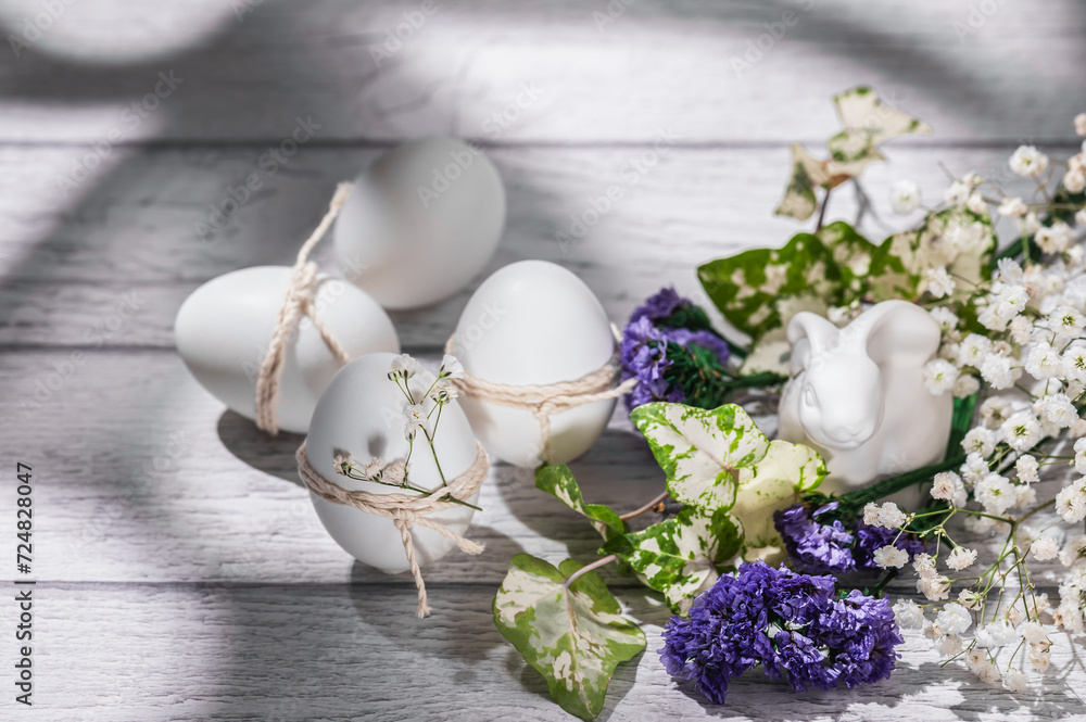 Easter eggs decorated with gypsophila sprigs, white Easter bunny on a white wooden background.Easter background.