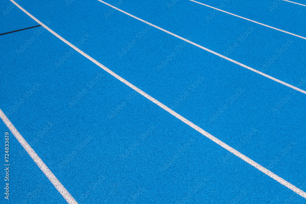 Blue Stadium track lanes with white stripes, an empty background suitable for copy space, represent the concept of physical sports and running, symbolizing commitment and pathways towards goals
