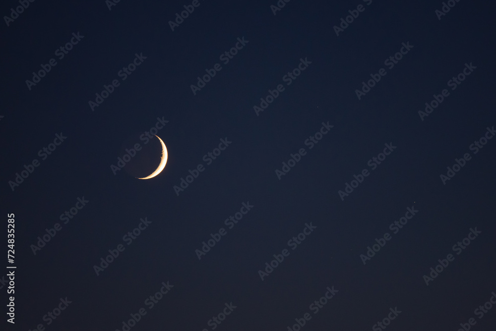 Young crescent moon on a clear sky at the end of the day in the summer Young crescent moon on a clear sky at the end of the day in the summer