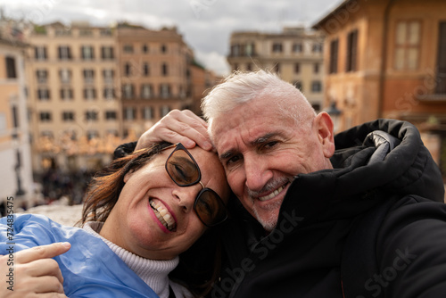 happy middle aged couple of tourists on vacation taking a selfie in front of the famous trinità dei monti staircase in rome photo