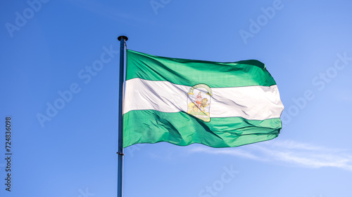 Flag of Andalusia waving in blue sky. Andalusian banner, Spanish federal state