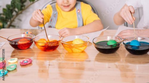 Children color eggs for Easter in glass plates.