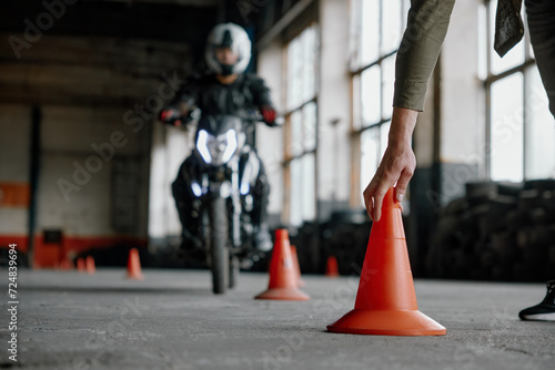 Motorbike driving school lesson with instructor putting cone on track photo