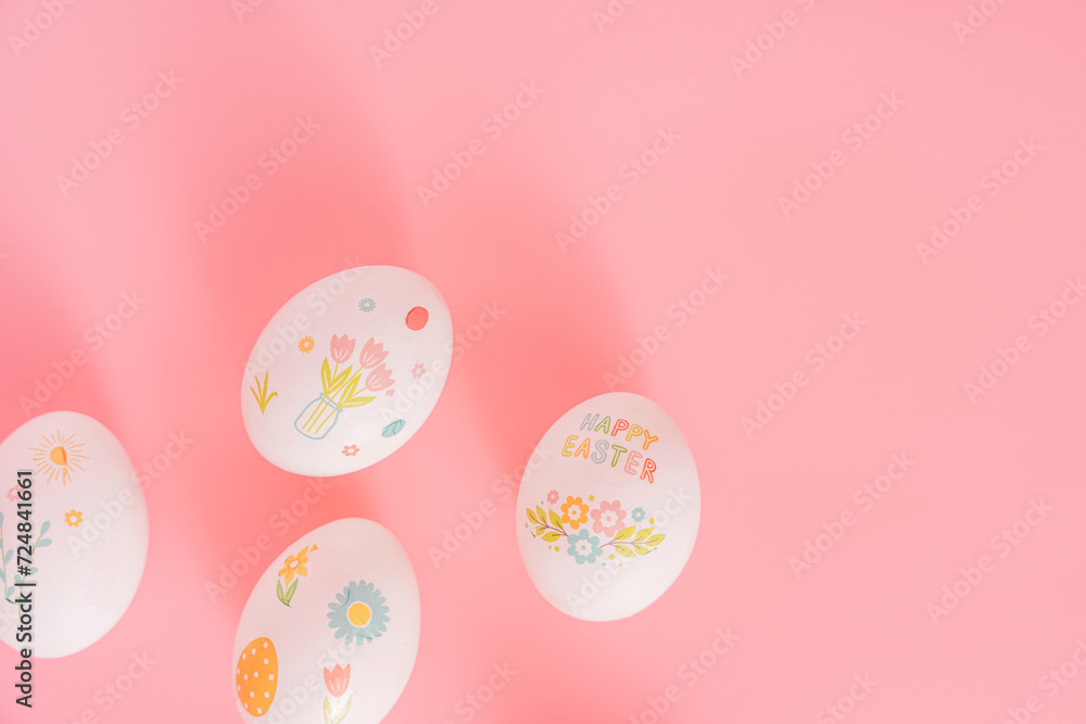 Easter eggs with drawings and stickers on a pink background.