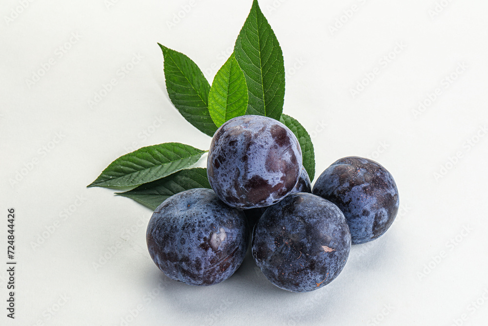 Raw purple plums heap with leaves Raw purple plums heap with leaves