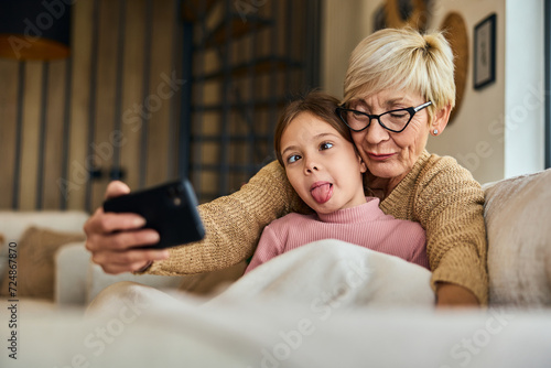 A grandma and her grandchild making funny faces while taking photos with a mobile phone. photo