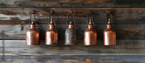 Antique copper olive oil cruets hanging on nails, against distressed wood photo